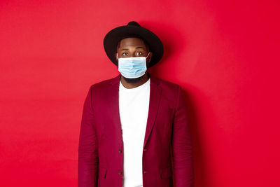 Portrait of man standing against red wall