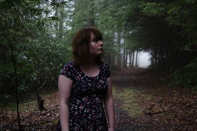 Beautiful young woman standing in forest