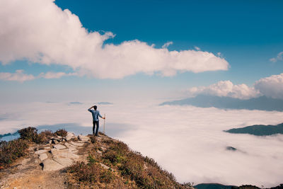 Man standing on rock against sky