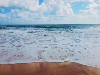 View of calm beach against cloudy sky