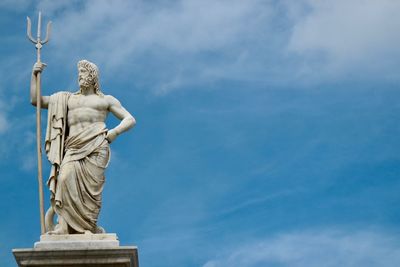 Low angle view of poseidon statue against sky