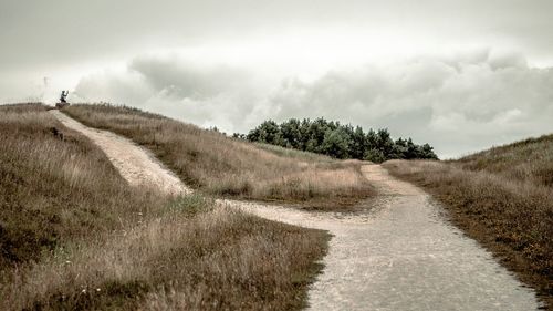 Scenic view of grassy field against cloudy sky