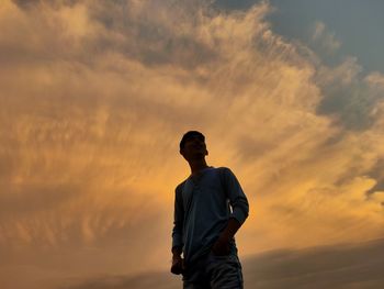 Low angle view of man standing against orange sky