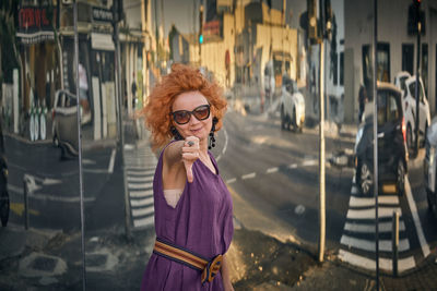 Portrait of woman gesturing while standing on street in city