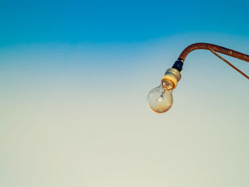 Low angle view of illuminated light bulb against sky