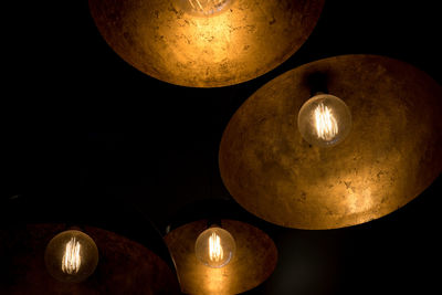 Low angle view of illuminated light bulbs in the dark