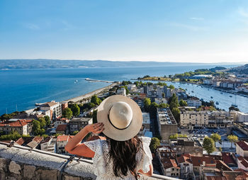 Rear view of woman standing on viewpoint above seaside town of omiš in croatia during summer holiday