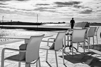 Rear view of woman sitting on chair at beach