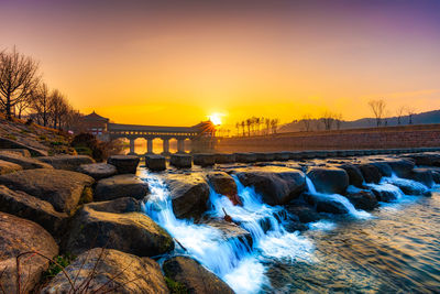 Scenic view of waterfall at sunset