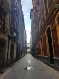 Empty road amidst buildings in city against sky