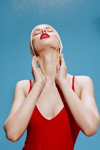 Portrait of young woman with eyes closed against blue background