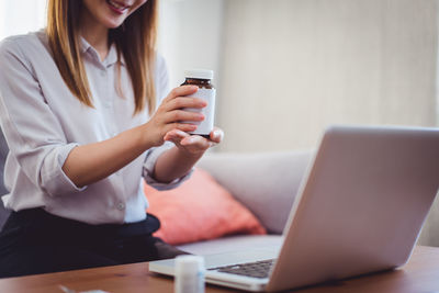 Midsection of woman using mobile phone while sitting on table