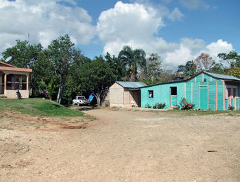 Houses on field by buildings against sky