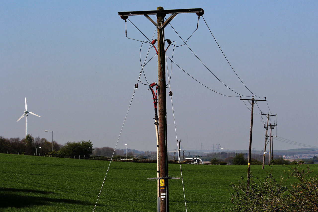 WINDMILLS ON FIELD AGAINST SKY