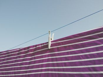 Purple laundry drying on clothesline against clear sky