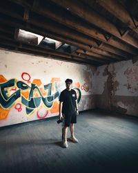 Full length of young woman standing against wall