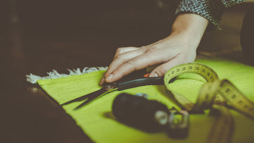 Close-up of woman holding scissor on table