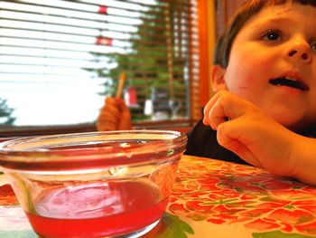 Close-up portrait of boy drinking glass on table at restaurant