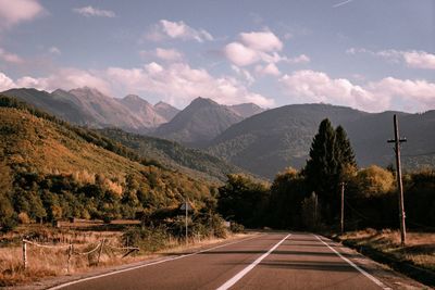 Empty road by mountains against sky