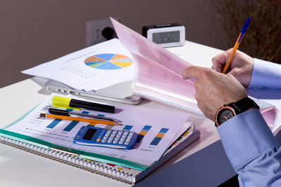 Cropped hand of businessman working on desk in office