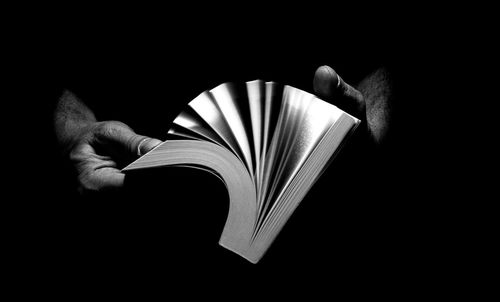 Midsection of person holding book against black background