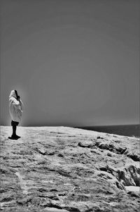 Man standing on shore against clear sky