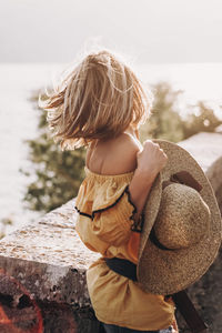 Girl from the back by the sea with a hat