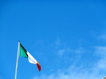 Low angle view of irish flag against blue sky