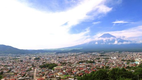 High angle view of cityscape by mountain against sky