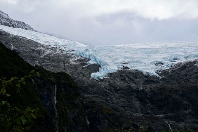 Scenic view of waterfall and a glacial against sky 