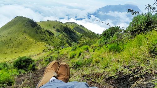 Low section of man standing on landscape against sky