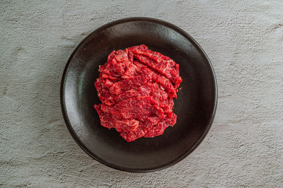 High angle view of red meat in bowl on table