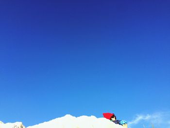 Low angle view of people on mountain against blue sky