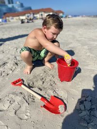 Toddler boy playing in warm sand during the day