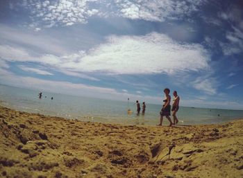 People playing at beach against sky