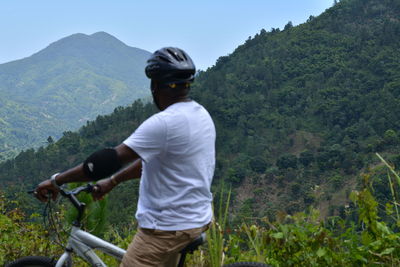 Rear view of man standing on mountain against clear sky