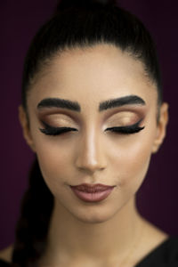 Close-up of young woman against black background