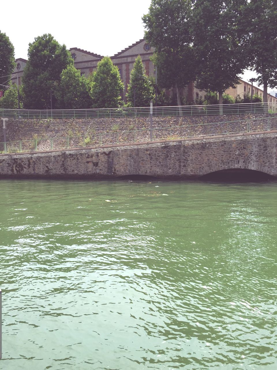 water, tree, waterfront, built structure, architecture, reflection, river, building exterior, tranquility, rippled, nature, tranquil scene, lake, beauty in nature, scenics, day, outdoors, clear sky, sky, no people