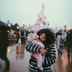 Mother carrying daughter while standing in city