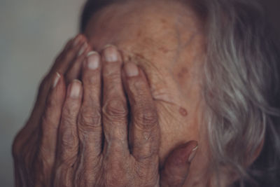 Close-up of senior woman covering face with hands