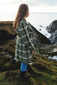Side view of woman standing on mountain by sea
