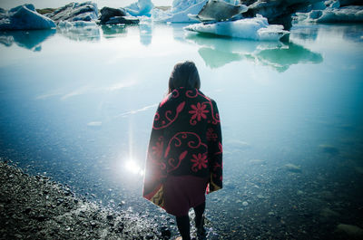 Rear view of woman standing by lake