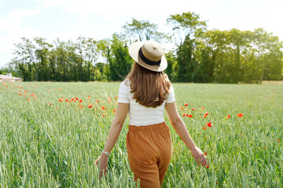 Rear view of woman wearing hat standing on field