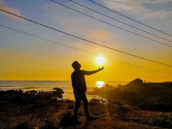 Silhouette man standing on land against sky during sunset