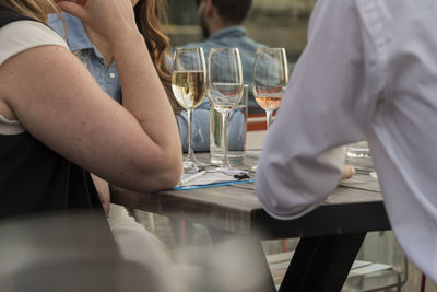 Midsection of people having wine at restaurant table