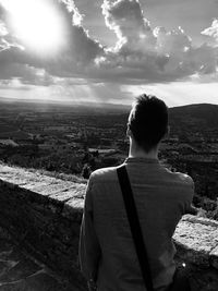 Rear view of man looking at cloudy sky