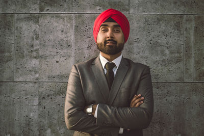 Portrait of smiling businessman wearing turban against wall
