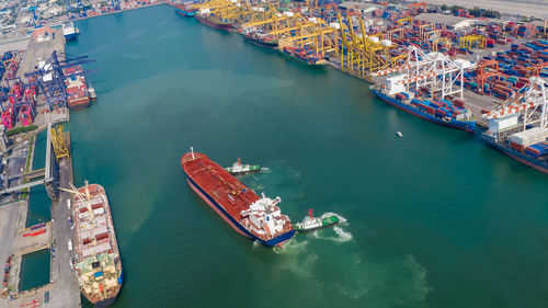 Aerial top view tugboat drag oil red ship tanker to dock for load and unloading and shipping 