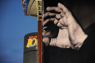 Low angle view of man holding illuminated lighting equipment against sky