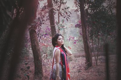 Full length of girl standing by tree in forest